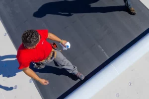 workers with a red tshirt installing a flat roofing