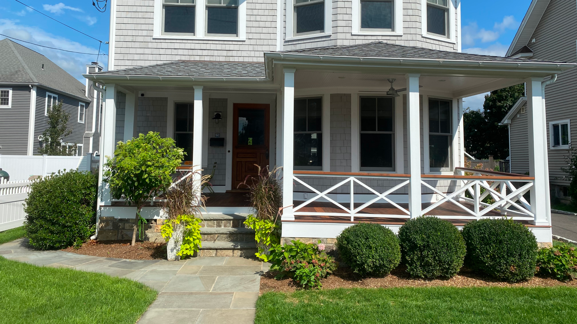 white house with a patio outside a walkway and some bushes